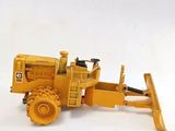 un petit bulldozer jaune posé sur une surface blanche