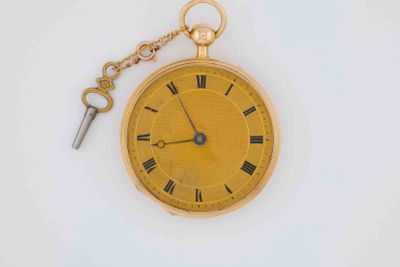 a gold pocket watch with a key attached to it