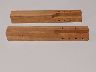 deux morceaux de bois percés de trous posés sur une surface blanche