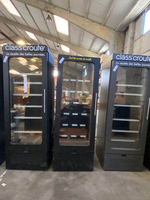 several glass door refrigerators are lined up in a warehouse