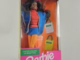 une poupée Barbie dans une boîte, posée sur une surface blanche, avec un fond blanc