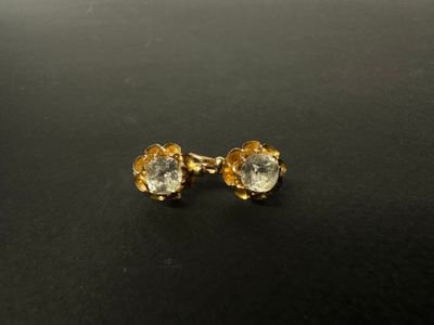 une paire de boucles d'oreilles dorées ornées de cristaux transparents sur un fond noir