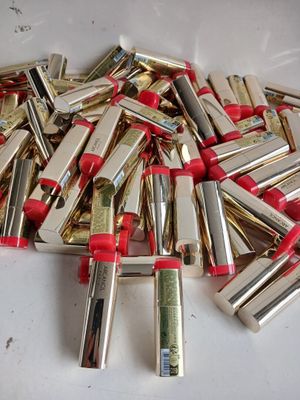 une pile de rouges à lèvres rouges et dorés posée sur une table blanche