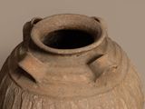 a large clay vase with a handle on a table