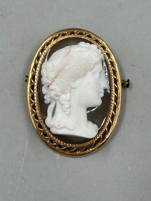 Une broche plaquée or représente le profil d'une femme.
