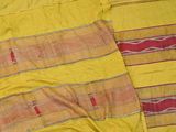 a cat laying on a bed next to a yellow blanket