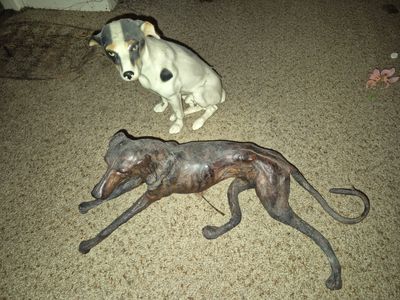 a statue of a dog laying on the floor next to a statue of a dog