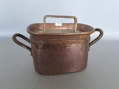 a small copper pot with a handle on a table