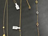 un lot de trois colliers posés sur une table, accompagnés d'étiquettes
