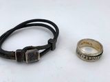 a silver ring and a leather bracelet on a white surface
