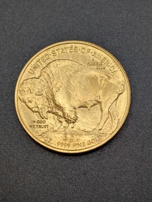 a close up of a gold buffalo coin on a black surface
