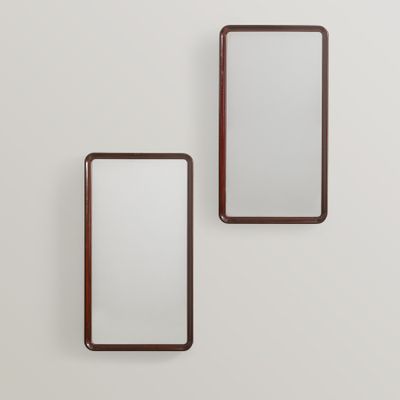 two rectangular mirrors mounted on a wall in a white room