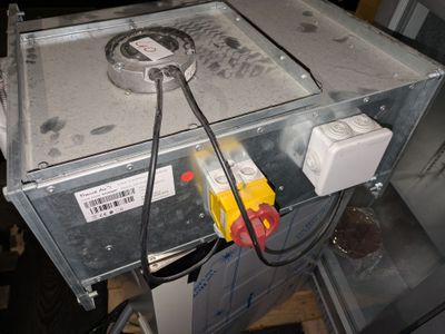 une boîte métallique à laquelle sont fixés des fils, posée sur une table