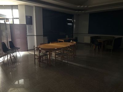des tables et des chaises dans une pièce, avec un tableau noir en arrière-plan