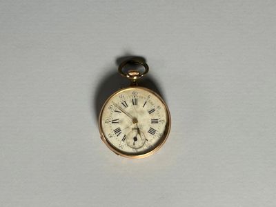 une petite montre de poche en or avec des chiffres romains