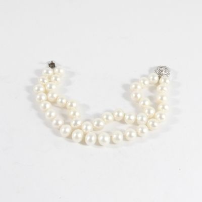 un gros plan sur un collier de perles blanches muni d'un fermoir en diamant