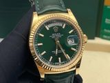 someone is holding a rolex watch in their hand on a table