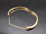 an image of a gold bracelet on a black surface