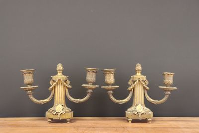 pair of antique brass candelabs on wooden table against grey wall