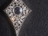 an image of a diamond shaped pendant with a blue stone in the center