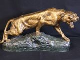 bronze sculpture of a lion on a rock on a black background
