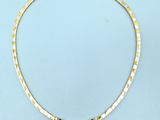 a gold necklace with multi colored stones on a blue background