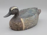 un canard en bois posé sur une surface blanche
