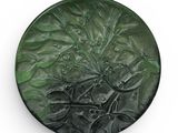 une assiette verte ornée d'un motif sur un fond blanc
