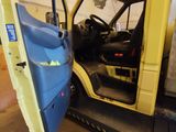 a yellow truck with a blue door open in a garage
