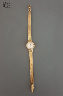 un gros plan d'une montre en or posée sur une surface grise
