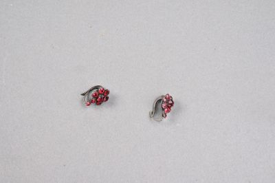 une paire de boucles d'oreilles rouges et argentées posées sur un fond blanc