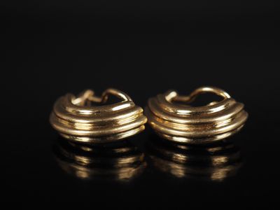 une paire de boucles d'oreilles en or sur une surface noire