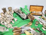 a lot of silverware on a table with a green cloth