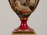 a red vase with a painting on it sitting on a table