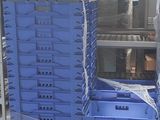 un homme debout à côté d'une pile de caisses bleues