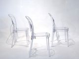three clear plastic chairs sitting next to each other on a white surface