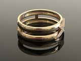 two gold rings on a reflective surface with a black background