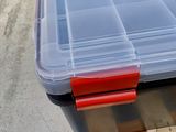 a plastic box with a red handle on a pallet