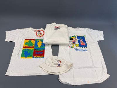 trois t-shirts et une casquette sont posés sur une table