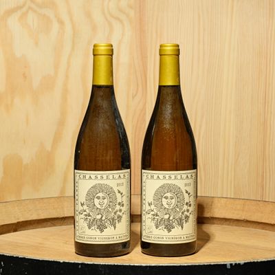 two bottles of wine sitting on top of a barrel