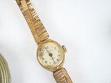 a gold wrist watch sitting on a table next to a vase