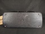 a black leather purse with a wooden handle on a black background