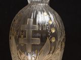un vase en verre orné d'une croix, posé sur une table