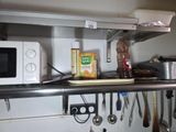 une étagère avec un micro-ondes, un four à micro-ondes et d'autres ustensiles de cuisine