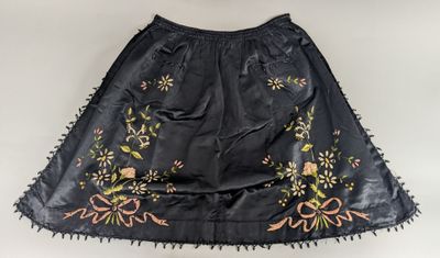 a black skirt with embroidered flowers and fringes on a white background