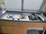 a small kitchen with a sink and stove in the back of a van