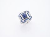 un gros plan d'une bague posée sur une surface blanche, sertie d'une pierre bleue