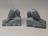 deux statues représentant un chien et un chat, posées sur un socle en pierre