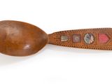brown wooden spoon with decorative design on it on a white surface