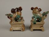 two ceramic figurines of a dog and a cat sitting on a chair